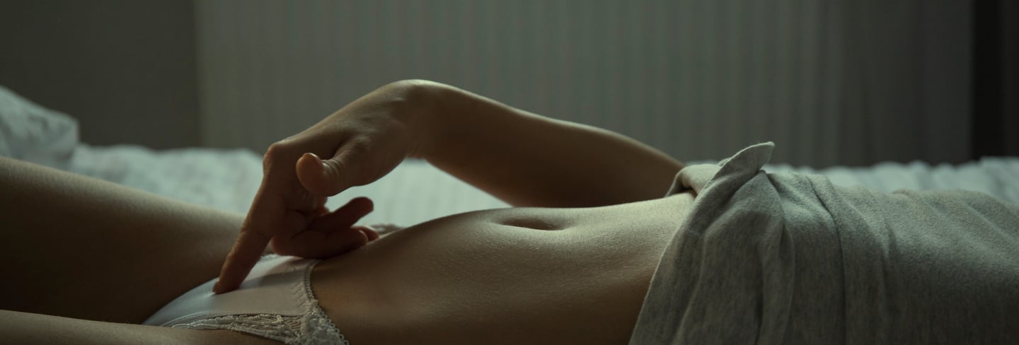 a woman in a white underwearsuit laying on a bed