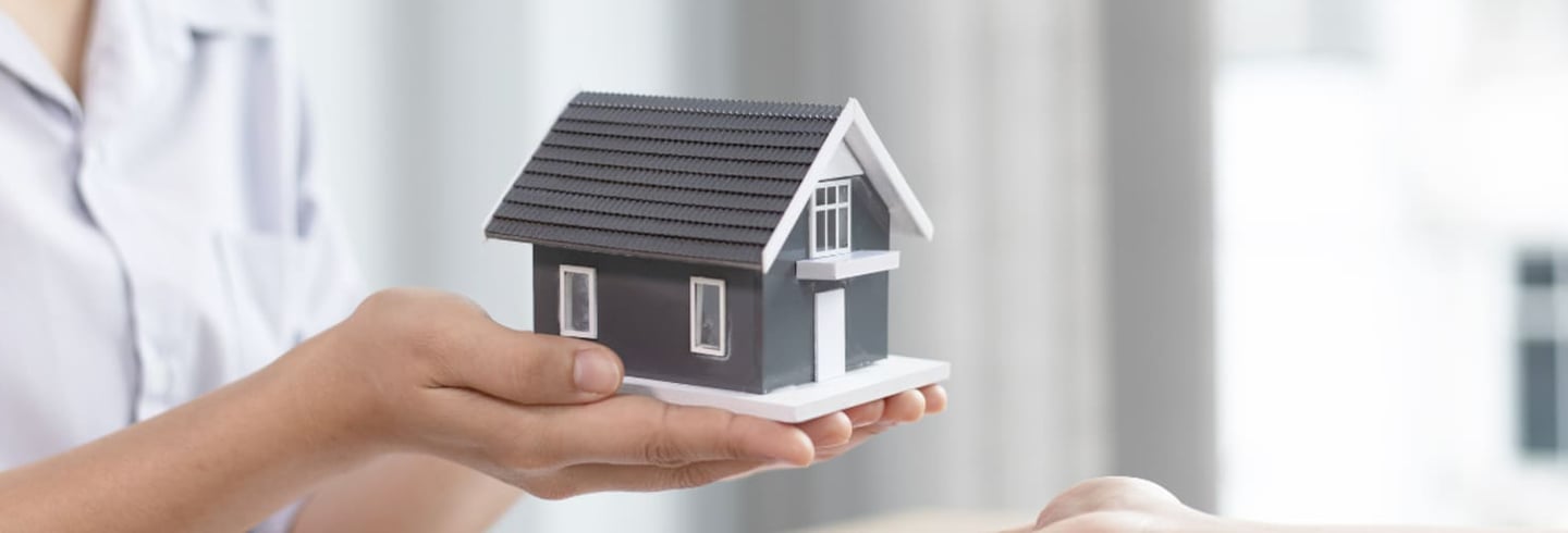 a woman holding a small house model
