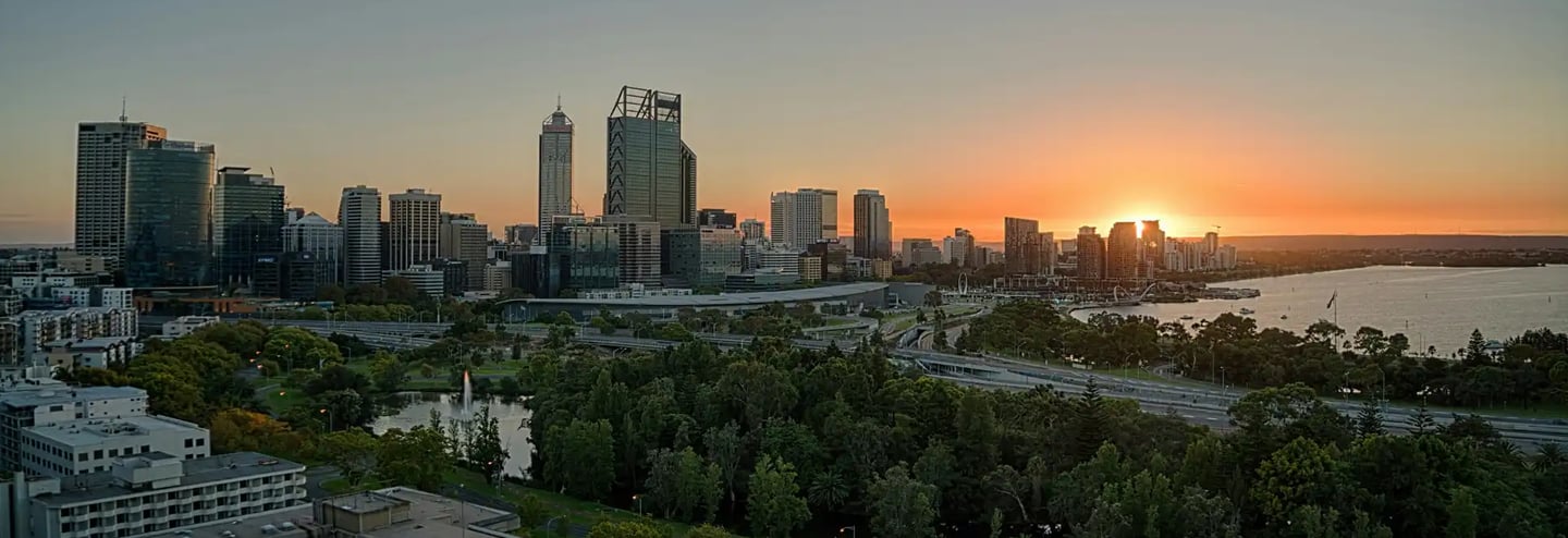 City skyline at sunrise with river and park bushland