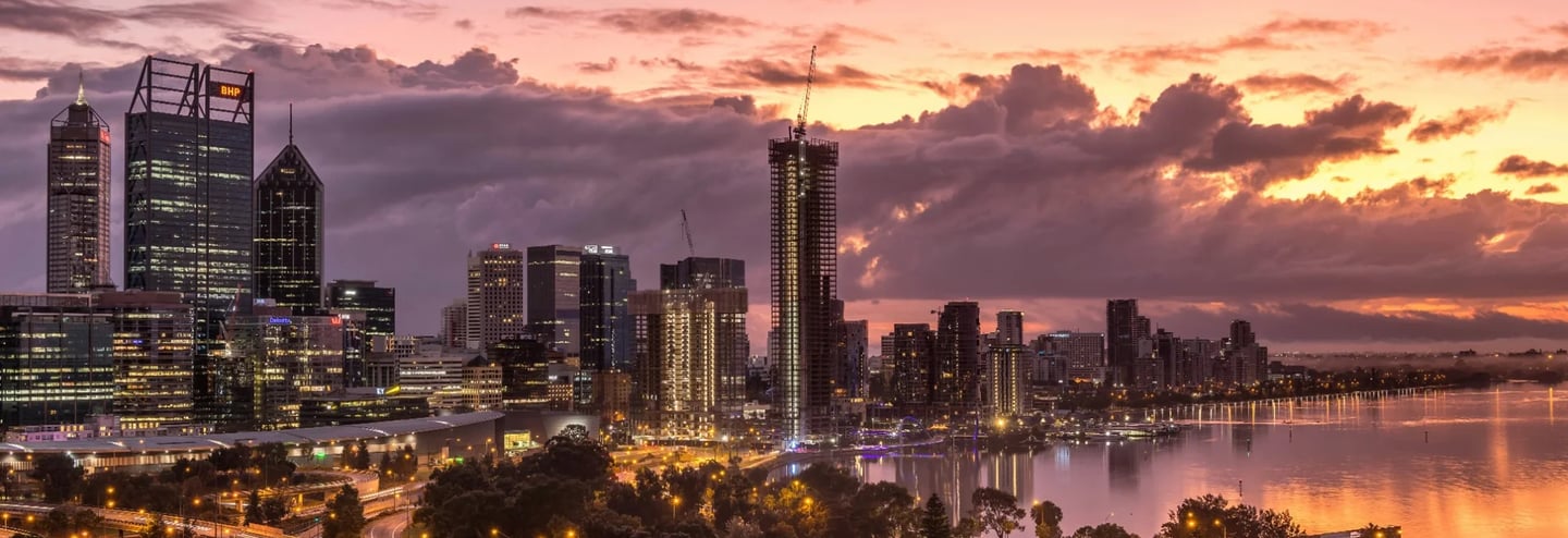 a city skyline with a river and a sunset