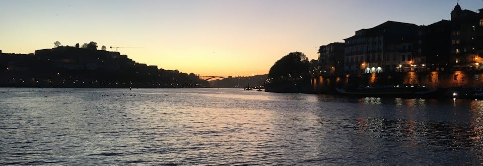 A sunset over the Douro river with a bridge and buildings
