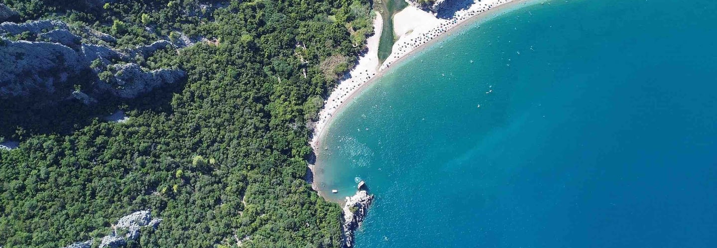 Olympos sahilinin ve antik kentin yeşillikler içindeki kıyısı, turkuaz deniz ve geniş kumsal havadan