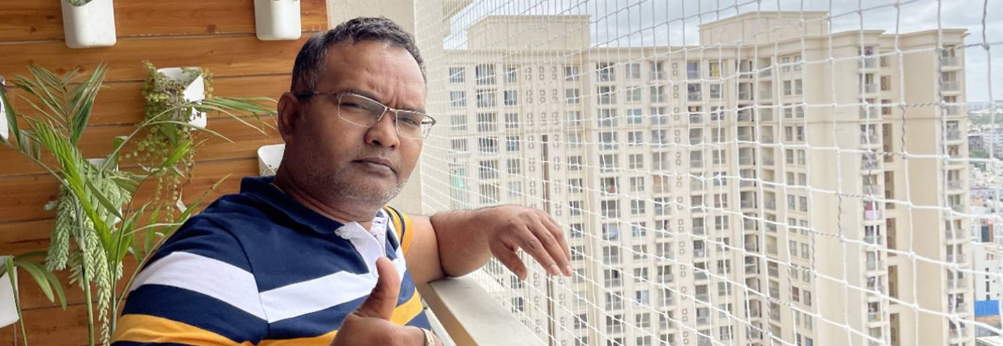 A friendly technician installing pigeon netting on a balcony in Bangalore.