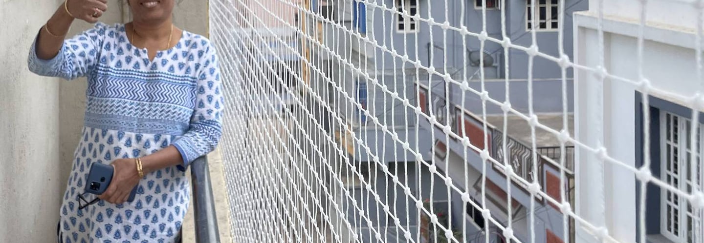 A friendly technician installing a balcony safety net on a sunny day in Coimbatore.