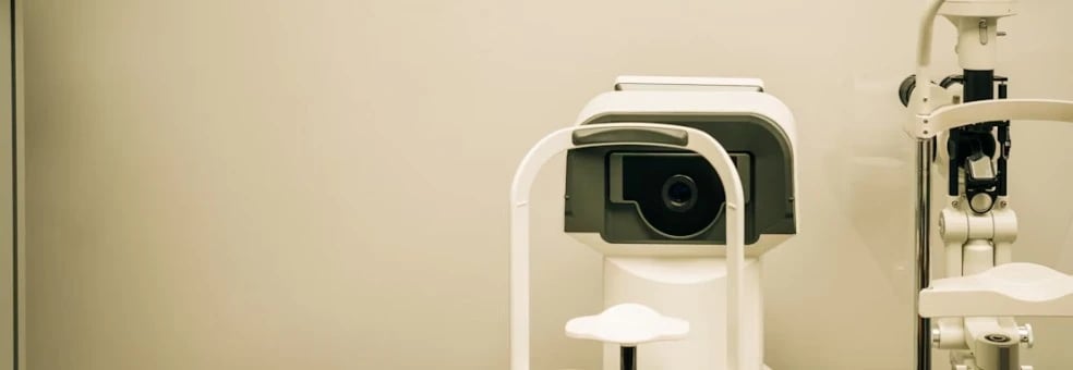 Optometry machine situated on an examination table, used for eye testing, in a clinical setting.