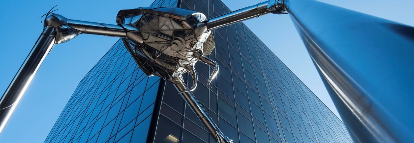 metal statue of futuristic bug in front of office building