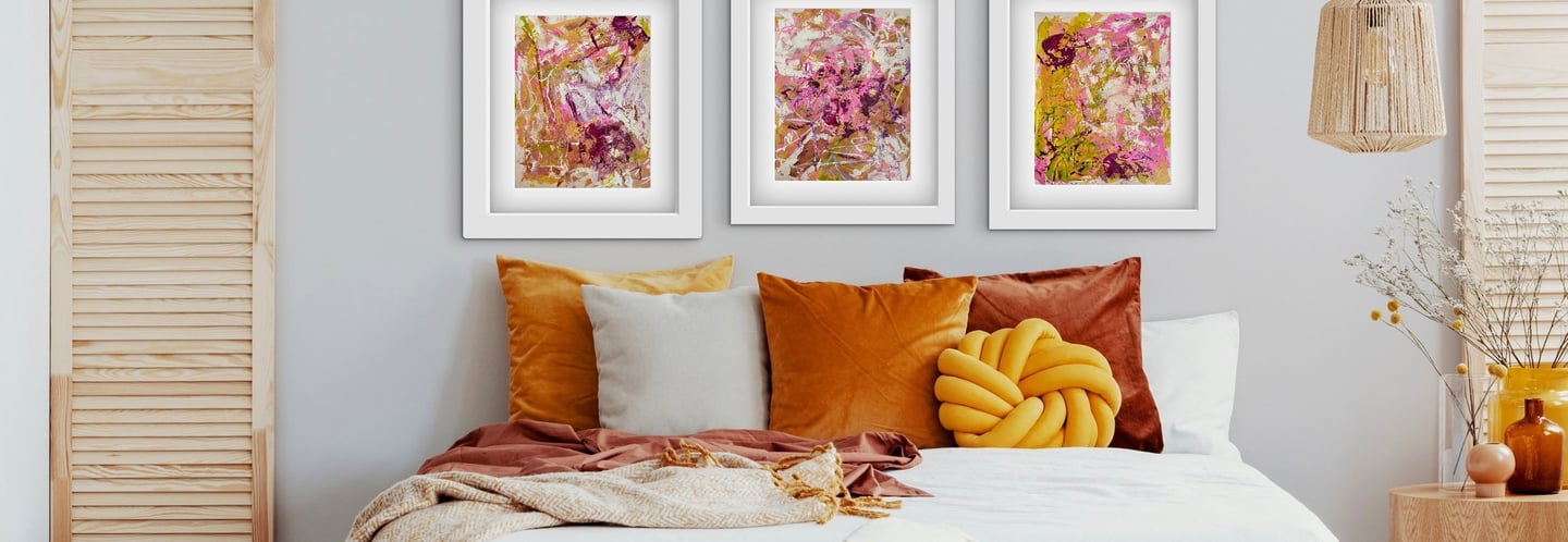 a bedroom with orange pillows and artwork used as a headboard