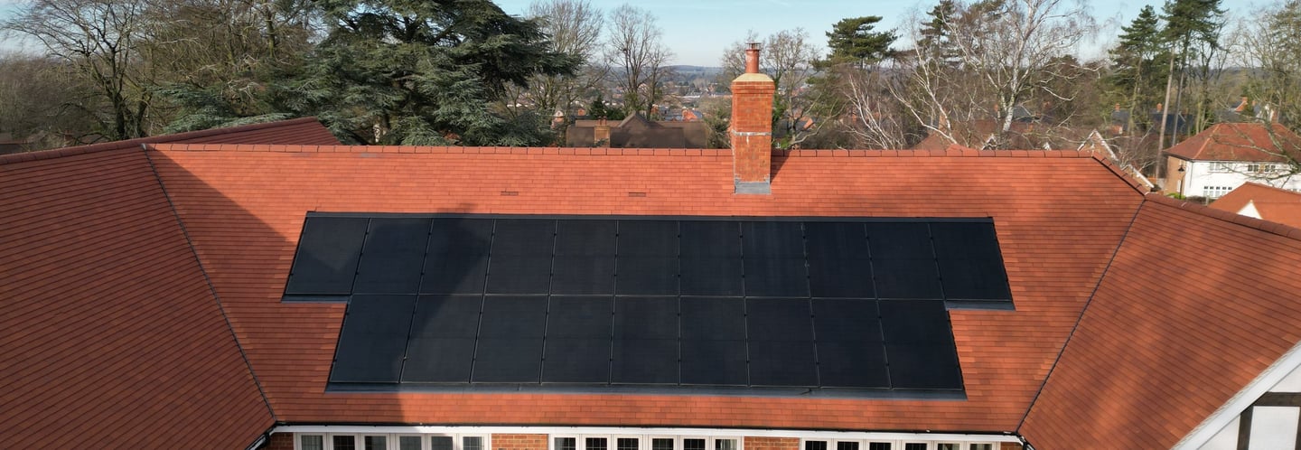 Aerial view of a residential brick house with black solar panels in Buckinghamshire