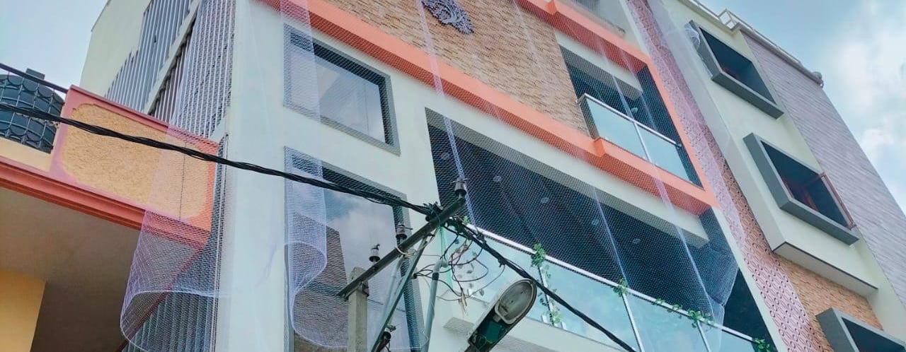 A friendly technician installing a balcony safety net on a sunny day in Coimbatore.