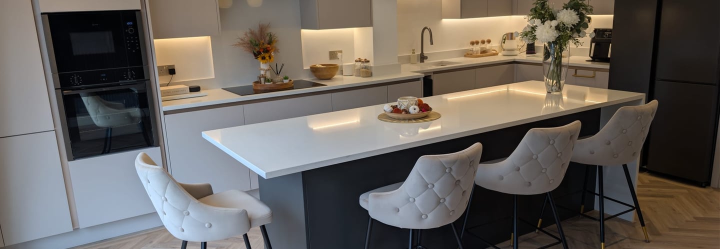 white kitchen, white comfortable stools, with flowers and fruit on the countertop