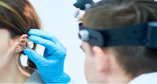 Otolaryngologist Dr. Porro uses a speculum and headlamp to perform a professional ear exam