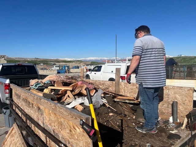 a man standing in trailer emptying it at the dump with a truck in the back