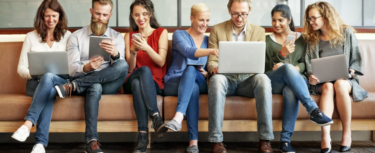 A welcoming community center with diverse people engaging around computers and digital devices.