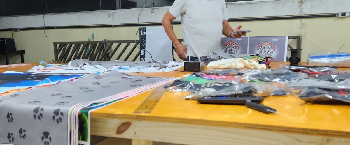 Imagem da mesa de corte da Persona estamparia, com vários materias e produtos sobre a mesma. 