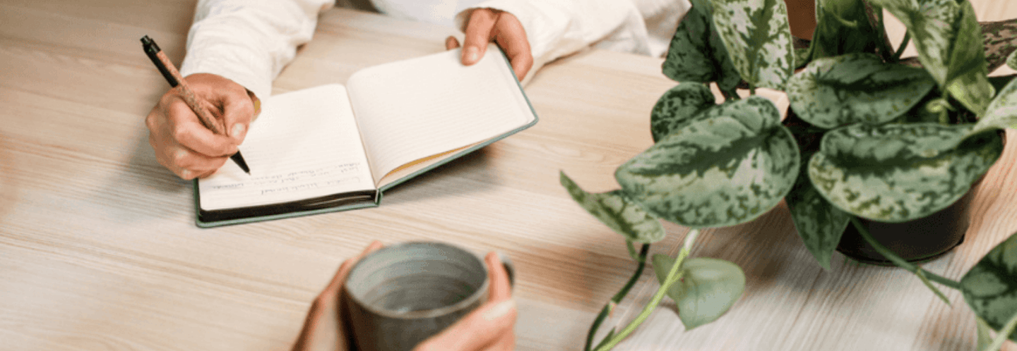 Jacquelien schrijft in haar notitieboek terwijl de klant praat met een kopje koffie in haar hand