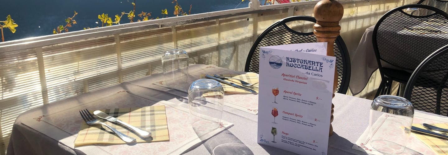 Tavolo apparecchiato con menù del Risotrante Roccabella sulla terrazza sul lago di lugano