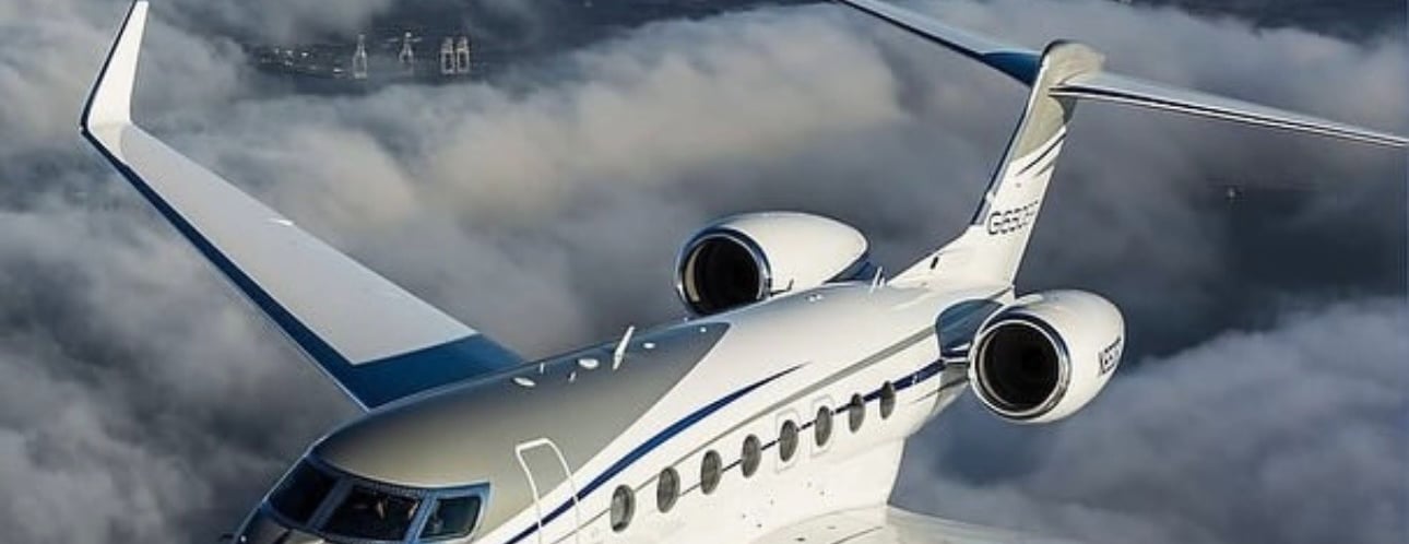 a white jet airplane flying over a cloud filled sky