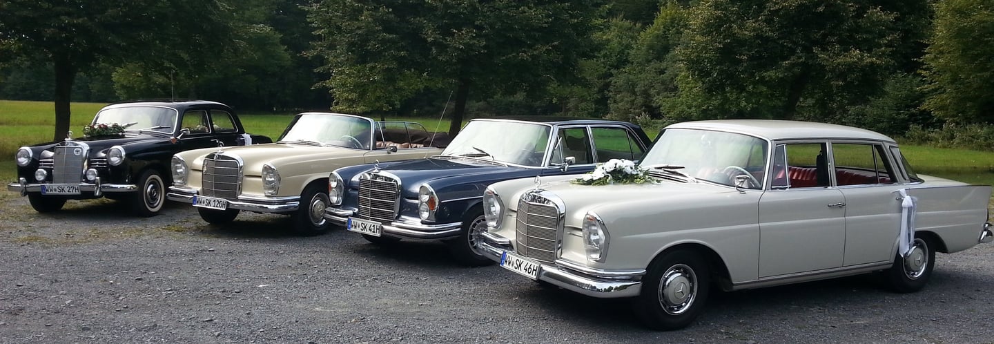 4 Oldtimer stehen in einem Bogen in einer Reihe. 