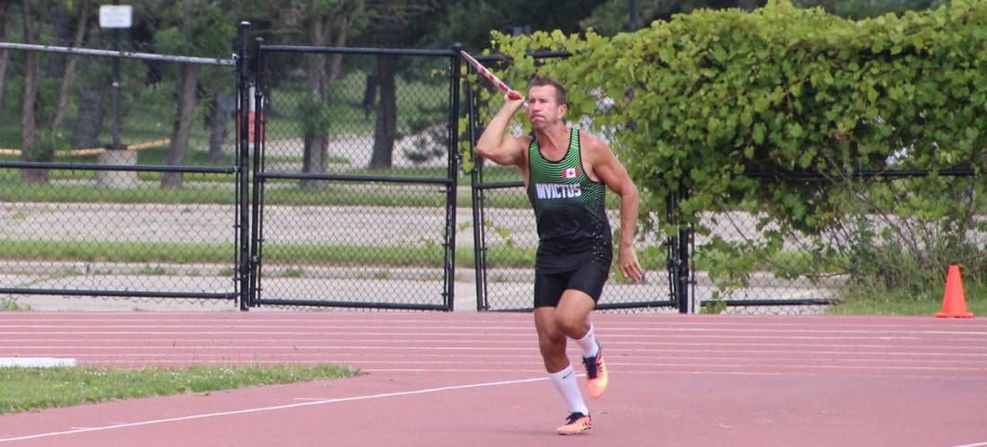 Male athlete mid-javelin throw in competition wearing Canada uniform at ThrowersClub track and field