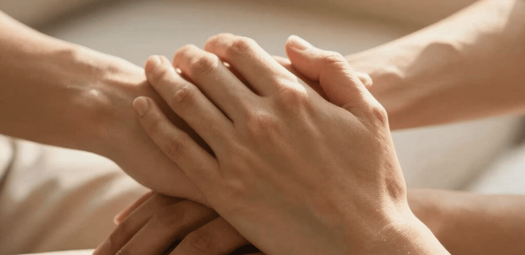 A gentle pastel illustration of two hands reaching out with a soft glowing heart between them.