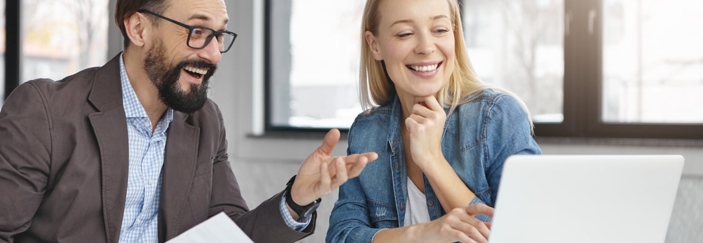 a man and woman sitting at a table with papers