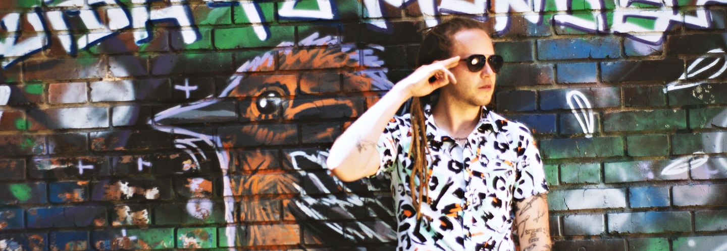 a man in a white shirt and sunglasses talking on a cell phone