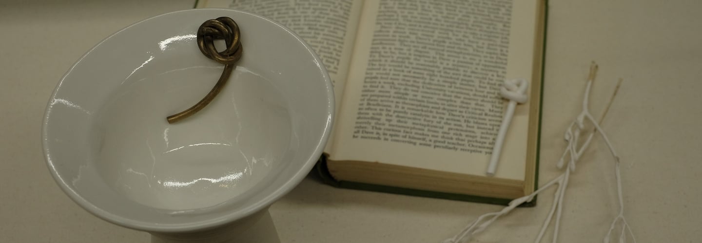 Assemblage including a porcelain vessel with sculptural bronze knot detail and Iris Murdoch novel 