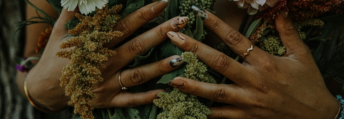 Une femme les mains vernies sur la poitrine, tenant un bouquet de fleurs.