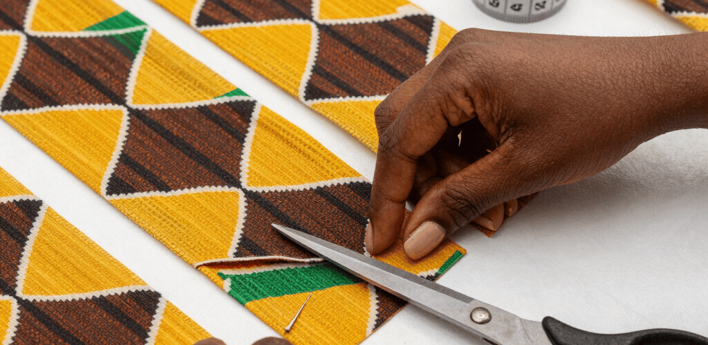 A close-up of hands sewing delicate fabric, surrounded by colorful threads and sketches of fashion designs.