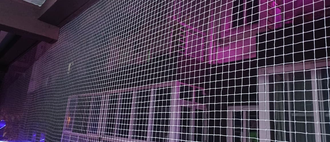 Technician carefully installing a sturdy safety net on a residential balcony in Hebbal.