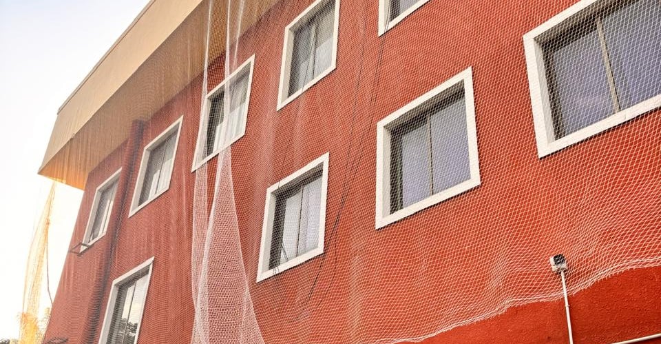 Technician carefully installing a sturdy safety net over a building duct in a bustling Malleshwaram 