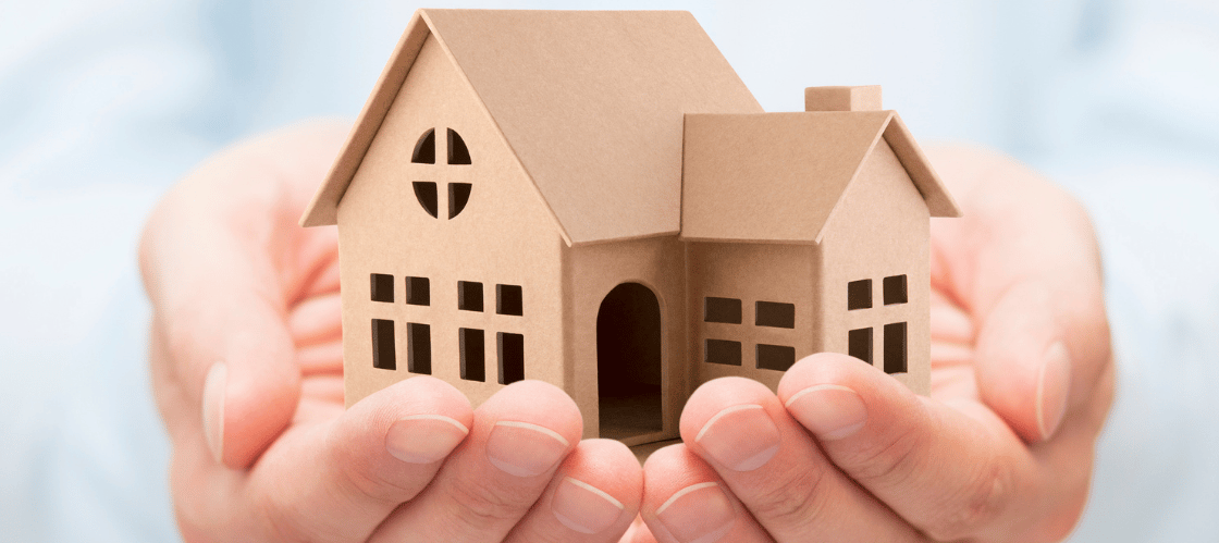 a person holding a paper house model of a house