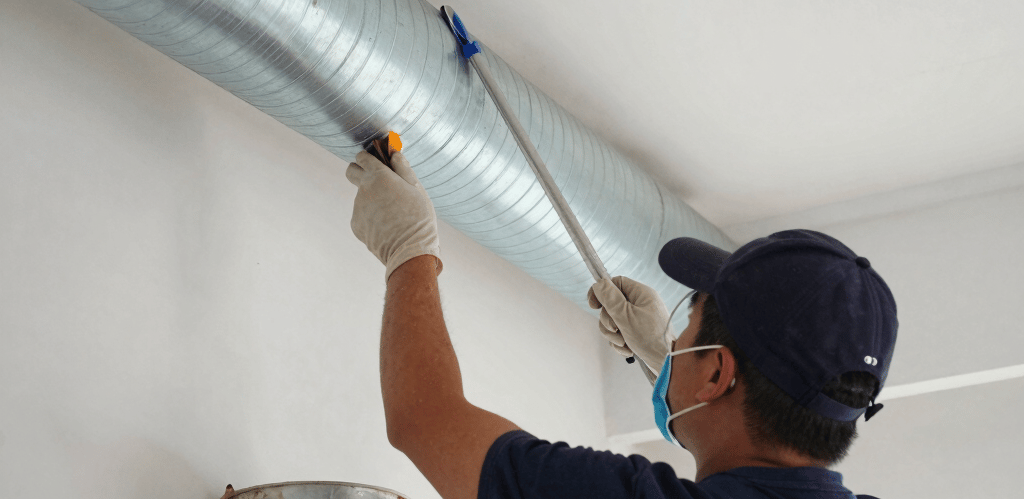 Technician carefully inspecting an air duct system with a camera in a bright, modern home interior.