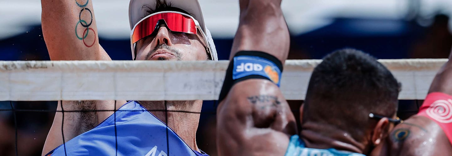 a man in a white shirt and sunglasses playing beach volleyball