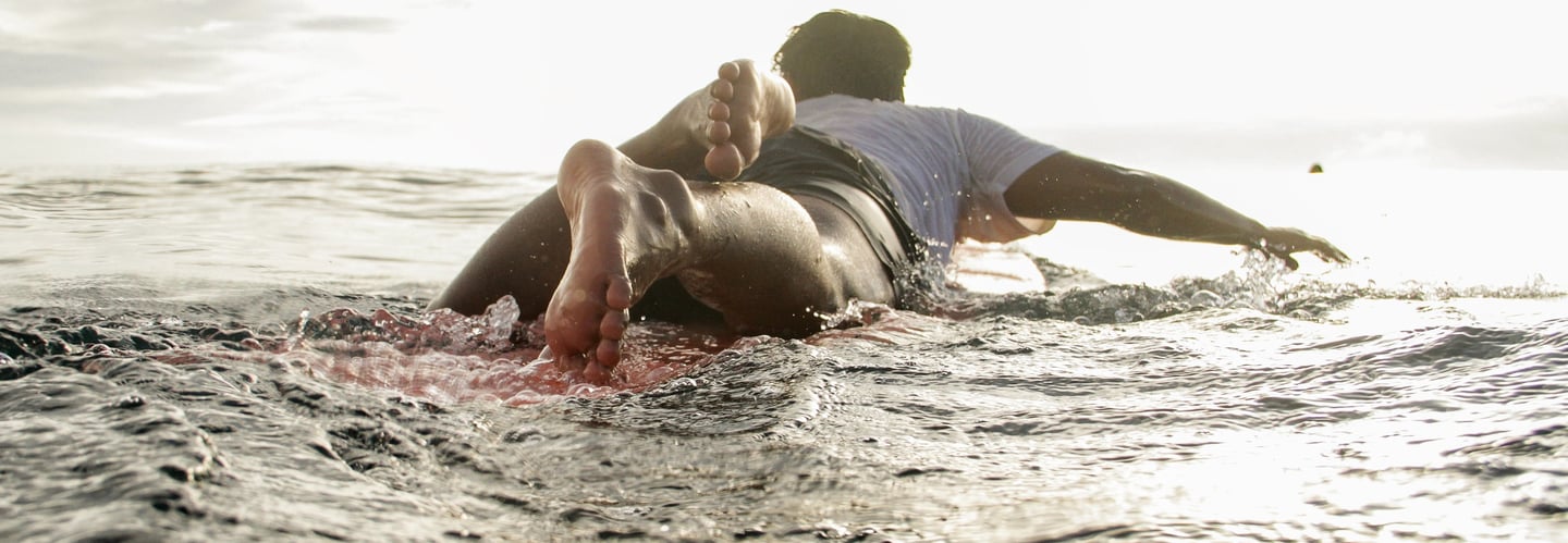 ucup laying on longboard surfboard in ocean
