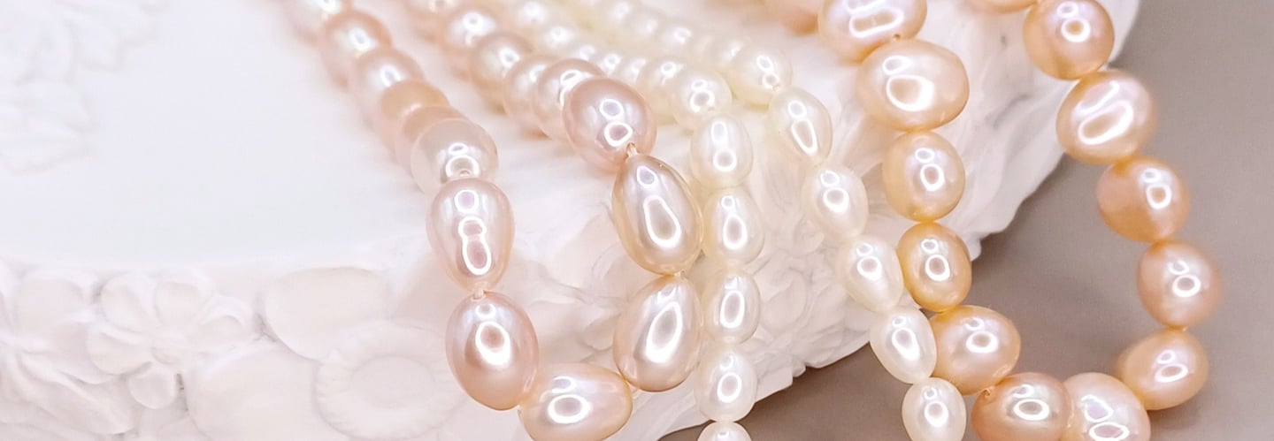 Strands of pink, ivory and peach freshwater pearls displayed on a neutural dish