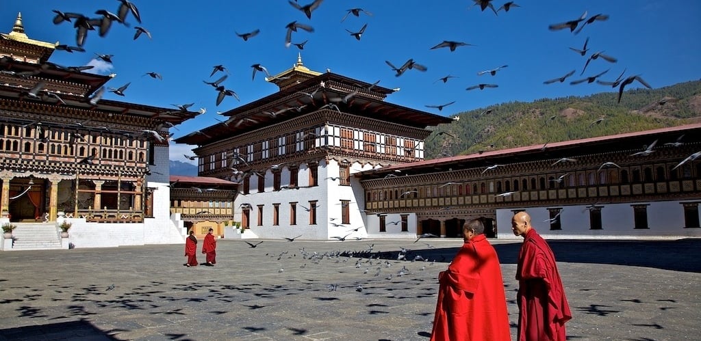 monks_in_the_courtyard_of_tashichho_dzong_feeding_the_birds
