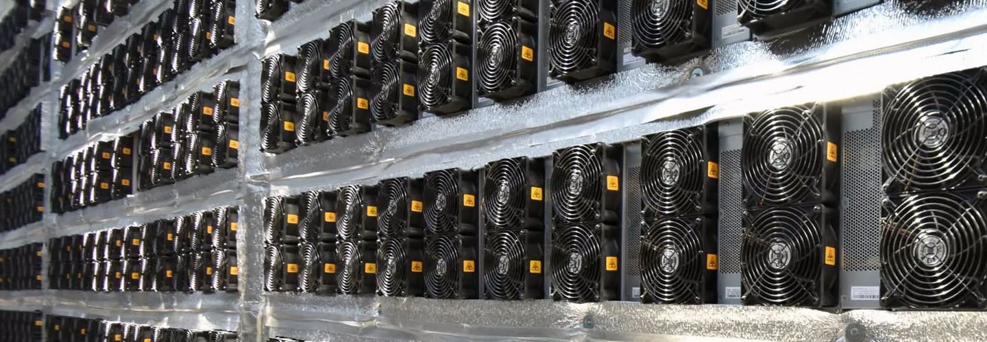 Rows of ASIC crypto mining hardware with cooling fans in a high-tech data center farm.