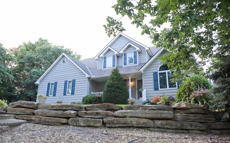 a house with blue horizontal siding, white windows and blue shutters