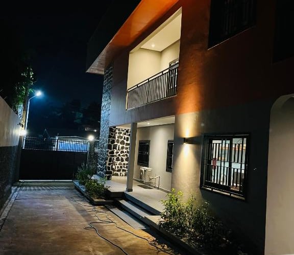 Modern residential house exterior with elegant outdoor lighting and stone accents at night.