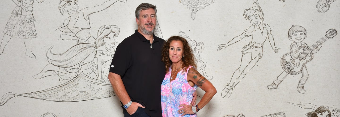 a man and woman standing in front of a wall with a mural of cartoon characters