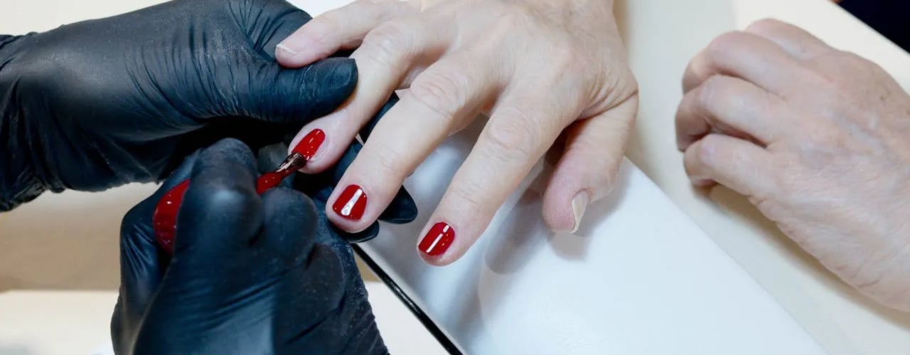 a person is getting their nails painted red