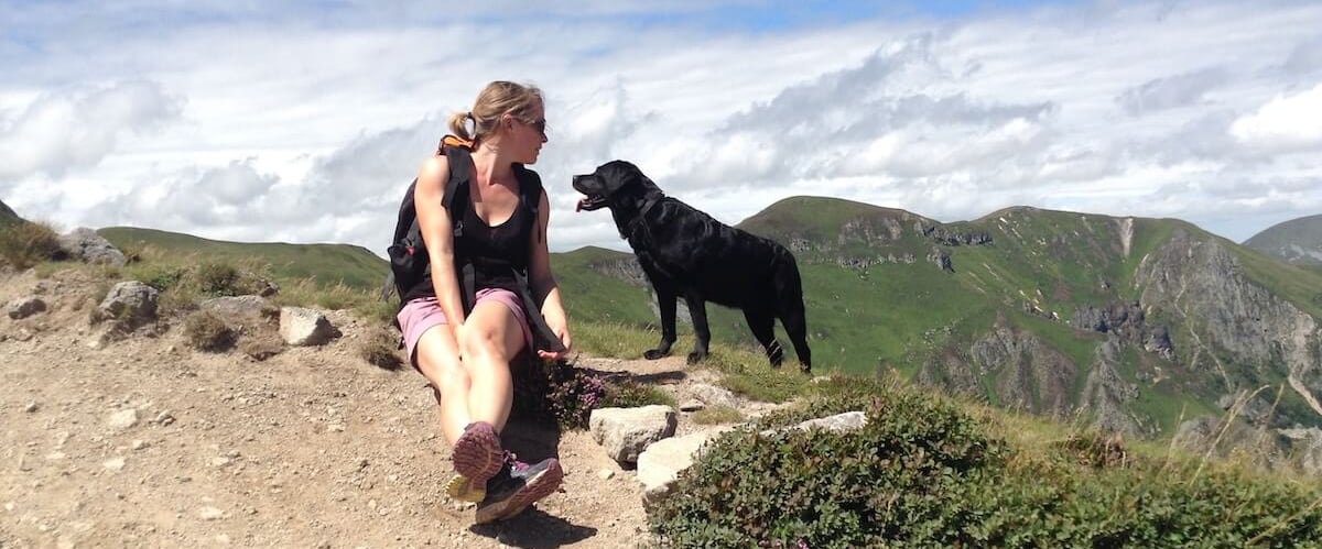 Une femme, éducateur canin, assise en haut d'une montagne avec son chien