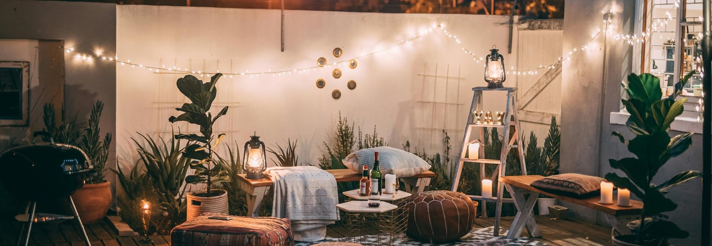 A cozy patio featuring decorative lights and vibrant plants, perfect for outdoor relaxation.