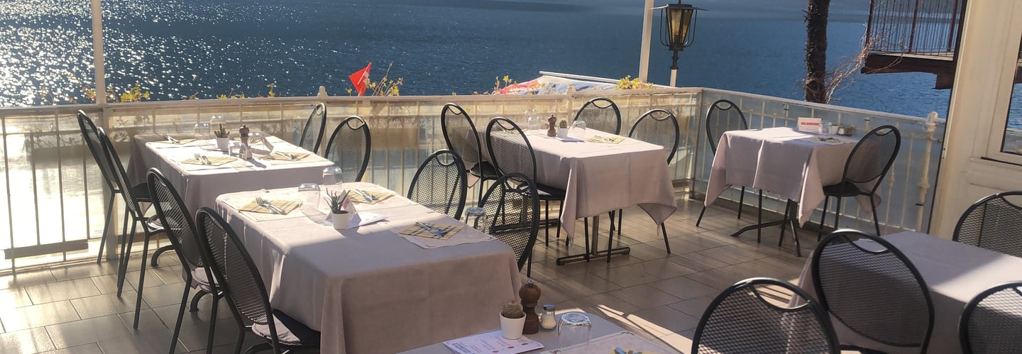 Terrazza di un ristorante con tavoli e sedie vista lago di Lugano