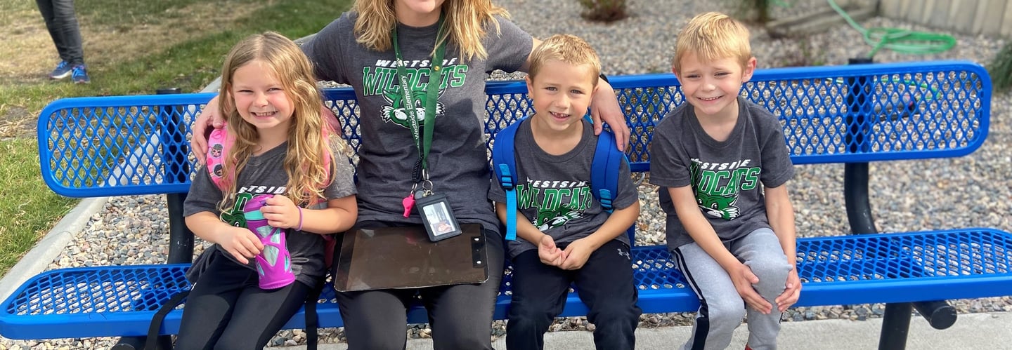 a woman sitting on a bench with three children