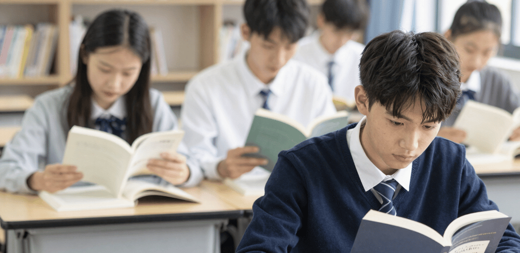 A focused student studying at a desk with a navy blue background and subtle yellow highlights.