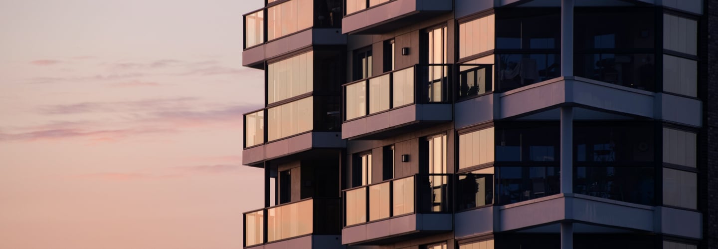 Edificio moderno, gris y negro, grandes ventales alumino negro, barandas de vidrio, atardecer