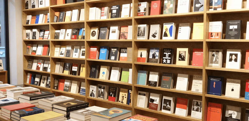 A vibrant display of art books and management titles stacked on a wooden table, showcasing Kalkfell's diverse publishing range.