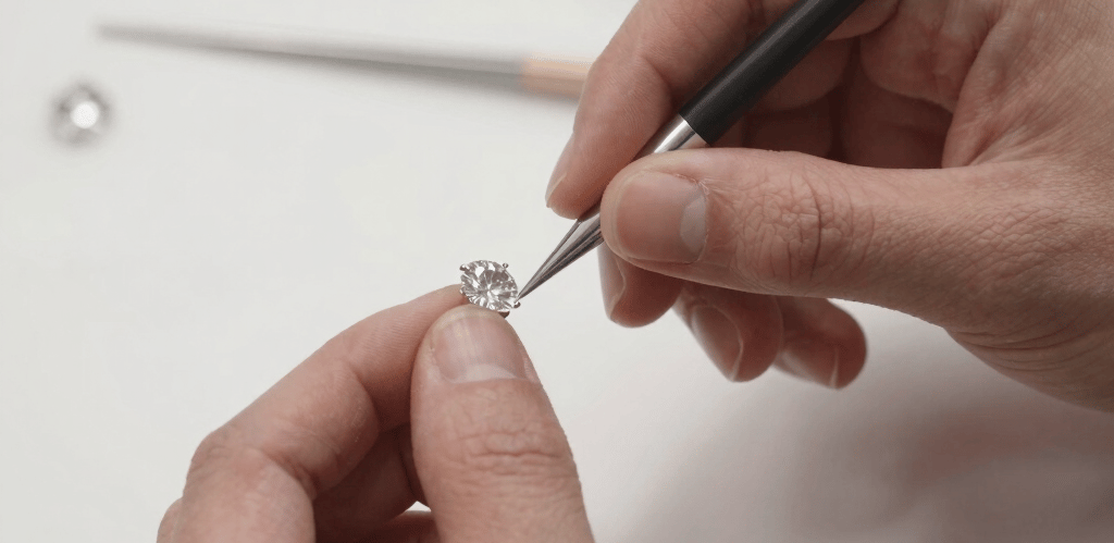 Close-up of a master jeweller delicately crafting a gold necklace with fine tools in a warm, inviting workshop.